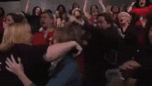 a crowd of people are sitting in a theater watching a movie and a woman is crying .