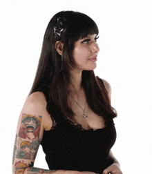 a woman with tattoos on her arm is wearing a black tank top and a necklace .