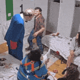 a man in a blue suit stands next to a man in a red shirt in a room with a number 1 on the wall