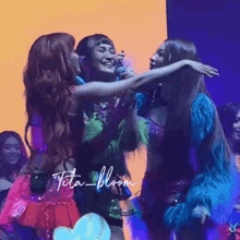 three women are hugging each other on a stage with the name tita bloom on the bottom