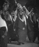 a black and white photo of a group of men walking down a street
