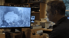 a man sits at a desk looking at a monitor that says army on it