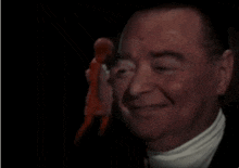 a man in a tuxedo is standing in front of a doll .