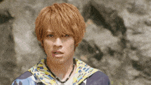 a young man with a necklace around his neck looks at the camera with a surprised look on his face