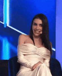 a woman in a white dress is sitting in a chair with a microphone .
