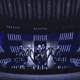 a couple of people dancing in front of a row of blue lights