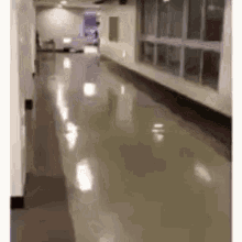 a long hallway in a building with a lot of windows and a person walking down it .
