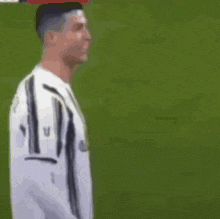 a man in a white shirt is standing on a soccer field and smiling .