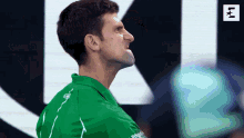 a man wearing a green shirt with the word lacoste on the back