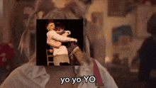 a woman is holding a man in her arms in front of a picture of a man hugging another man .