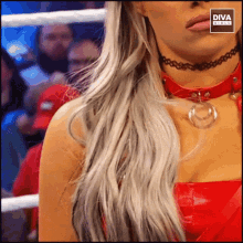 a woman wearing a choker and a red top is standing in a boxing ring ..