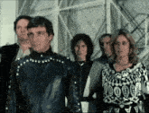a group of people are standing next to each other and one of them is wearing a black jacket