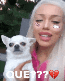 a blonde woman holding a small white dog with que written on the bottom
