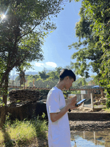 a young man in a white shirt is looking at his phone