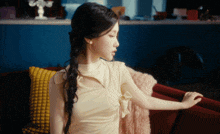a woman in a yellow dress is sitting on a red couch with a yellow pillow