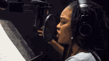 a woman wearing headphones and a ws logo on her ear is singing into a microphone