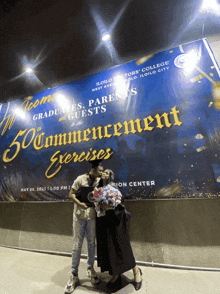 a man and woman are posing in front of a sign that says 50 commencement exercises