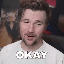 a man with a beard is wearing a white shirt and making a funny face .