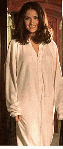 a woman in a white shirt is standing in a doorway smiling .