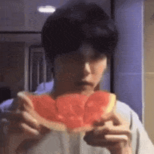 a man is eating a slice of watermelon with a fork .