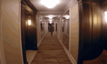 a woman is walking down a long hallway with mirrors on the walls