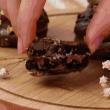 a close up of a person holding a piece of chocolate on a wooden table