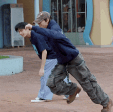 a man in a blue sweatshirt with the letter n on it is carrying another man on his back