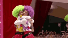 a couple of clowns hugging each other on a stage .