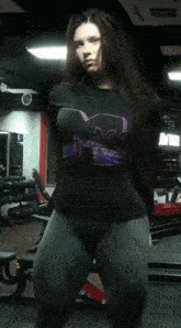 a woman in a gym wearing a black shirt that says " mass "
