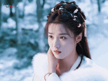 a woman in a white fur coat stands in the snow with chinese writing on the bottom