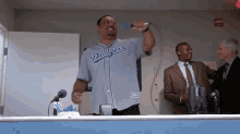 a man in a dodgers jersey is holding a microphone