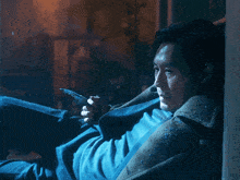 a man leaning against a wall holding a knife in his hand