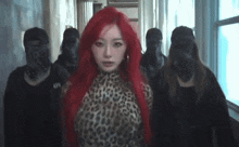 a woman with red hair is standing in a hallway with a group of people standing around her .