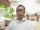 a man wearing glasses and a plaid shirt is sitting in a living room