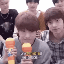 a group of young men are sitting around a table holding a toy .