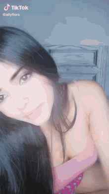 a woman in a pink bra looks at the camera with a tiktok watermark on the bottom right
