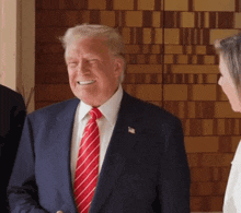 a man in a suit and tie smiles while talking to a woman