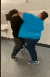 a man in a blue shirt is carrying another man in a black shirt .