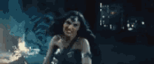 a woman in a wonder woman costume is standing in the dark .