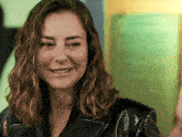 a woman wearing a black leather jacket is smiling