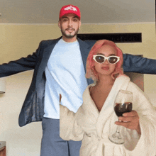 a man in a suit and a woman in a robe holding a glass of wine