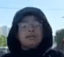 a close up of a person wearing glasses and a hood .