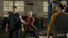 a man in a netflix shirt is standing in a garage with two other men