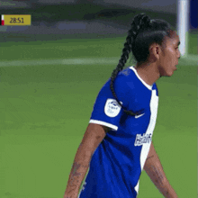 a female soccer player wearing a braided ponytail is standing on a field