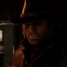 a man wearing a cowboy hat and a leather jacket is standing in a dark room .