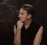 a man in a black tank top is talking in front of a dragon poster