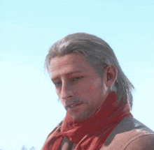 a man with long hair and a scarf around his neck looks down