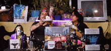 two men are sitting at a table with a sign that says " satan city "