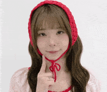 a woman wearing a red knitted headband and a pink top