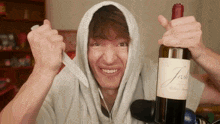 a man in a hoodie is holding a bottle of jesh wine